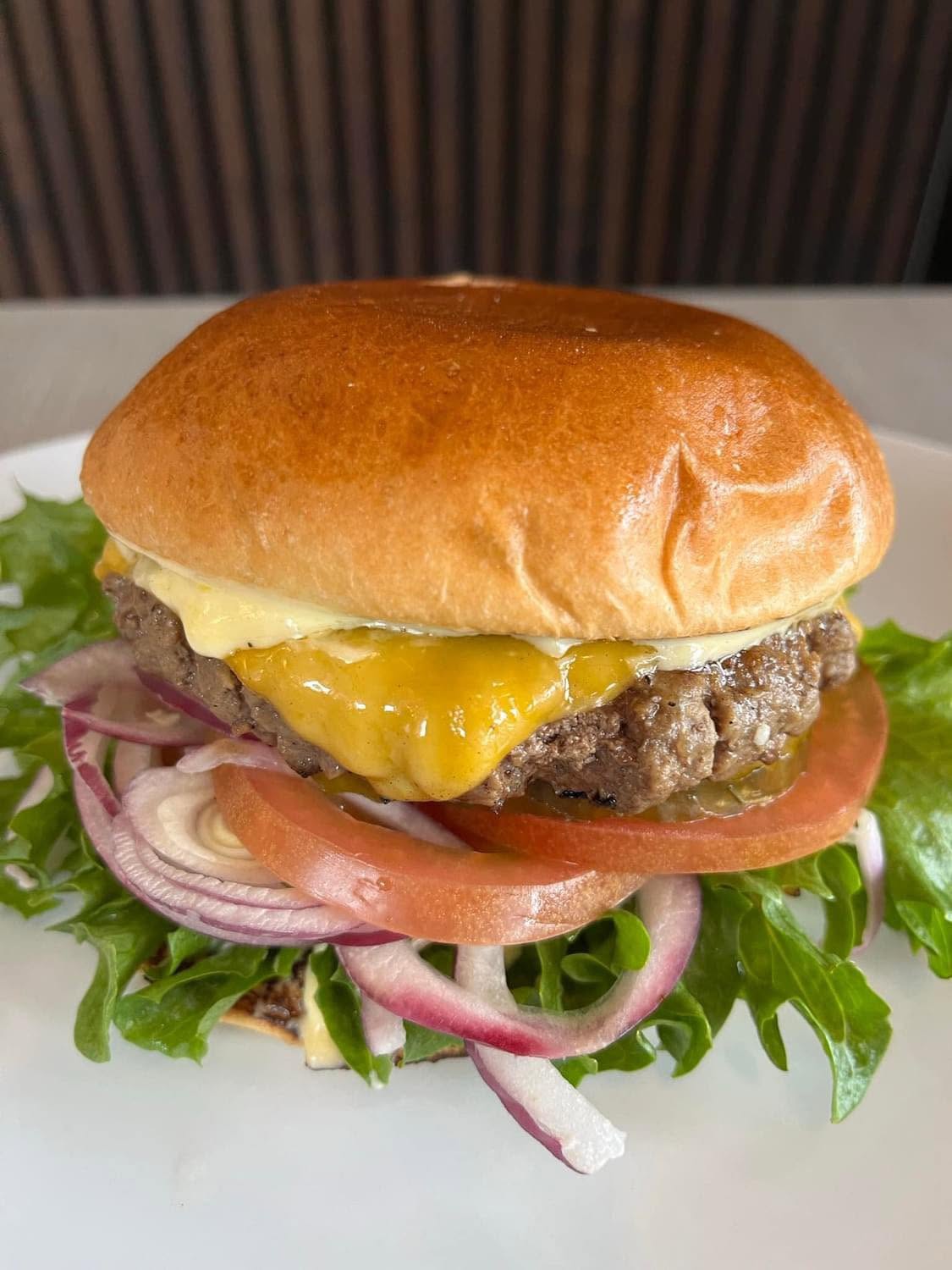 Carlsvognens kårede cheeseburger med smeltet cheddar, tomat, rødløg og salat i en blank briochebolle