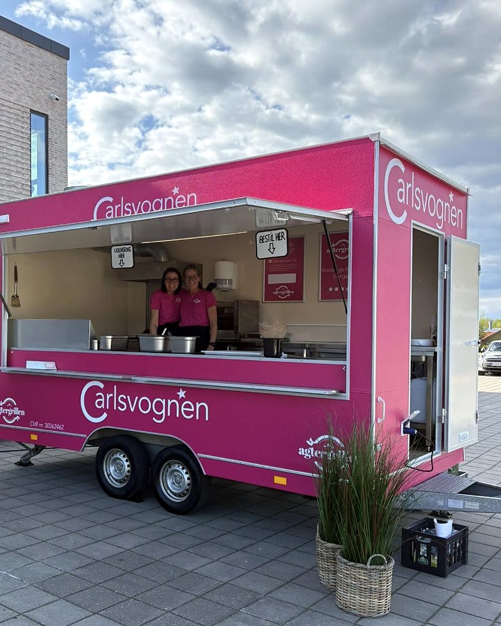 Den pink Carlsvognen med lugen åben og to smilende medarbejdere klar til at tage imod bestillinger
